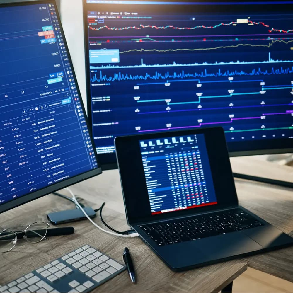 Desk with trading monitors and a laptop